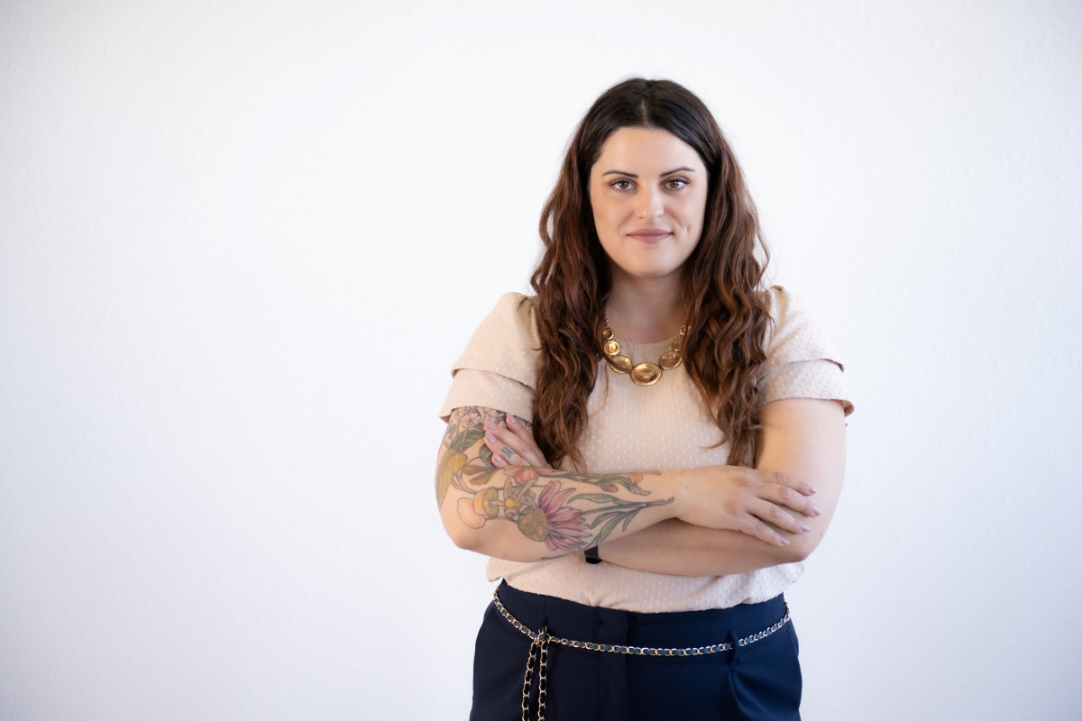A confident woman standing with her arms crossed, representing the power of delegation in leadership and business.