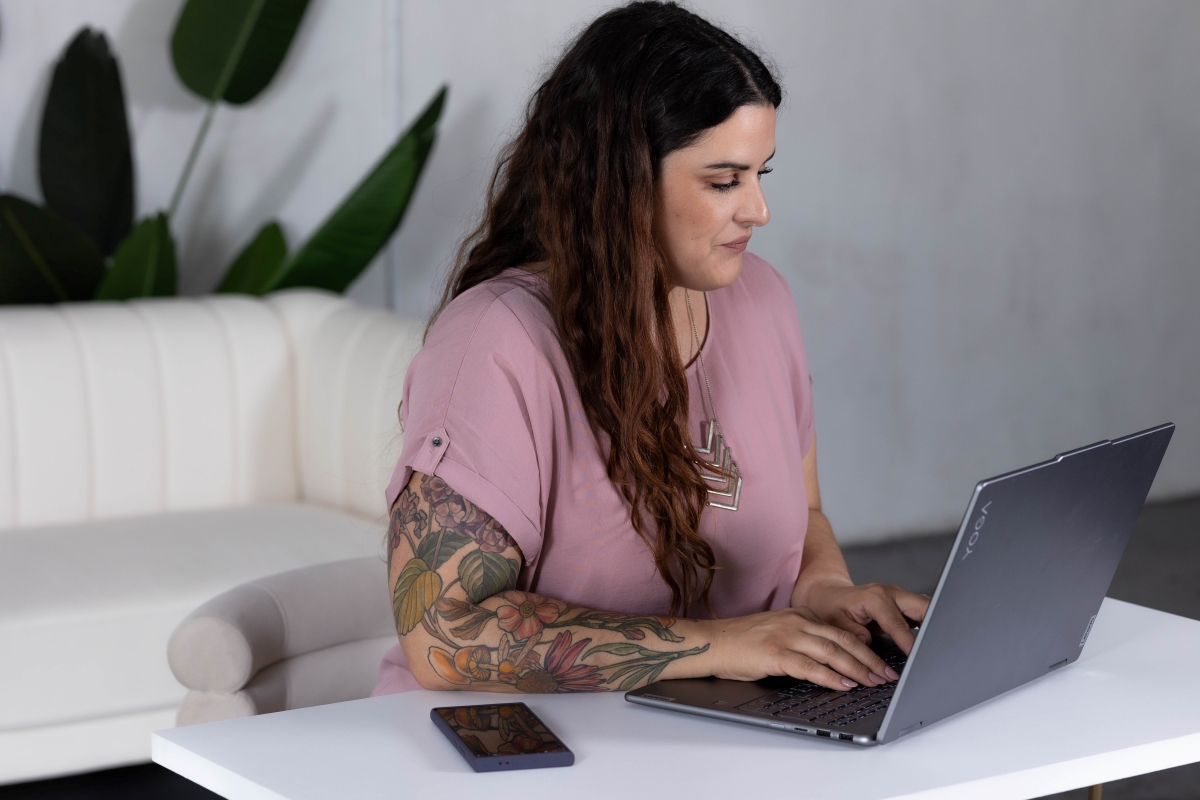 Business professional with tattoos working on a laptop, focusing on business processes.