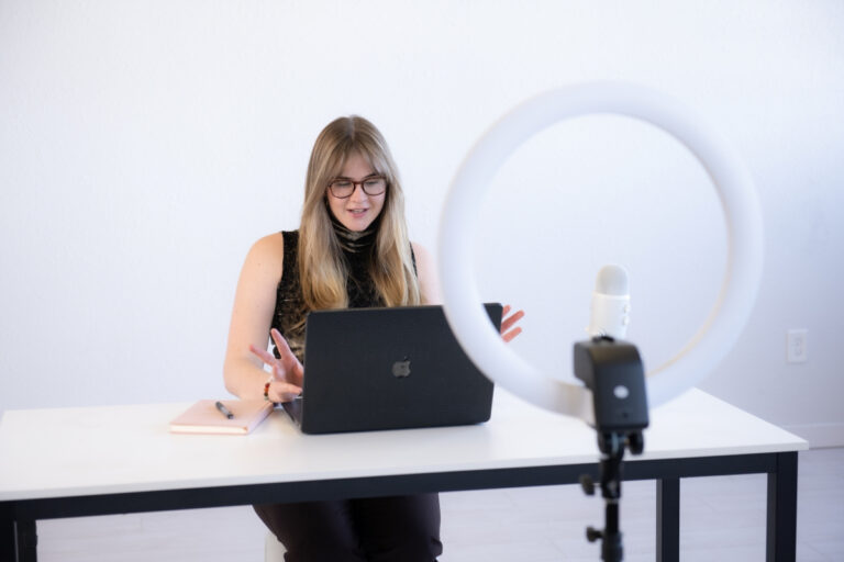 Woman hosting a virtual meeting with a laptop, ring light, and microphone — showcasing the benefits of hiring a virtual assistant for business efficiency.