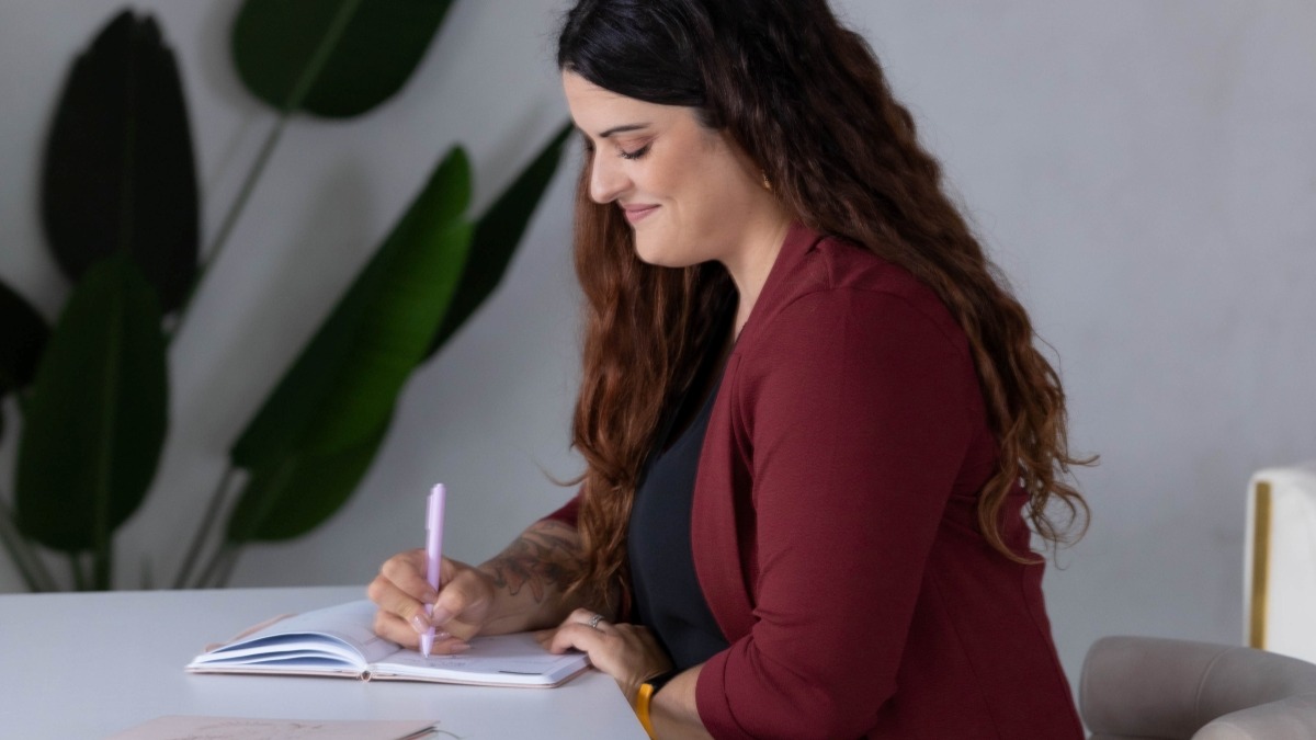 Professional woman sitting down at desk writing out real examples of process optimization.