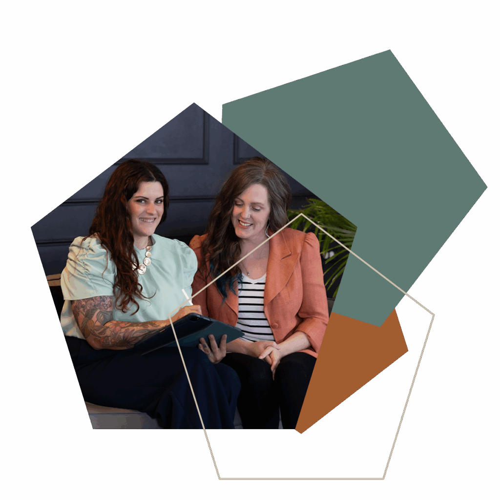Two women collaborating on a tablet during a business operations strategy meeting.
