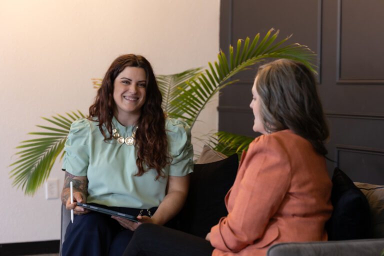 Two professional women discussing business strategy to improve operational efficiency in a modern office setting.